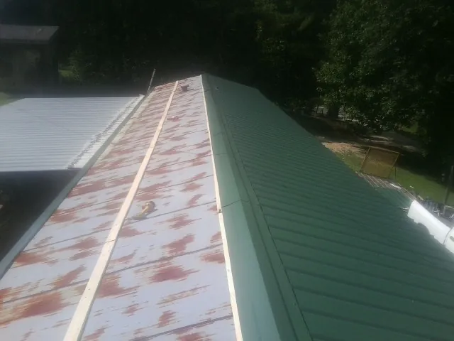 Old rusted panels beside newly installed green metal roofing — Wind Damage Roof Repair by Roofing Brothers in Evanston