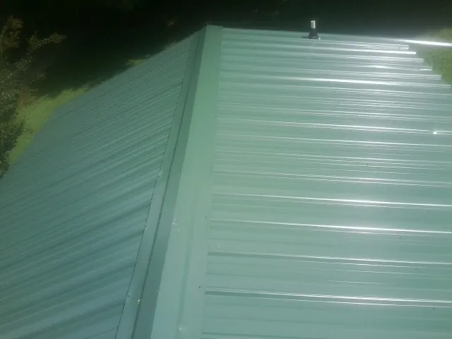 New green metal panels meeting at the ridge of a roof — Flat Roof Repair work by our crew in Evanston