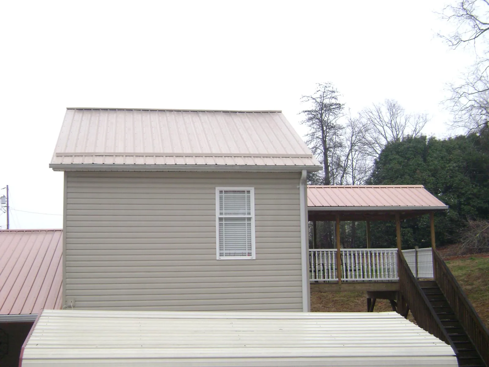 Tan metal roofs on a two story addition and attached porch, from a Roof Replacement job in Evanston