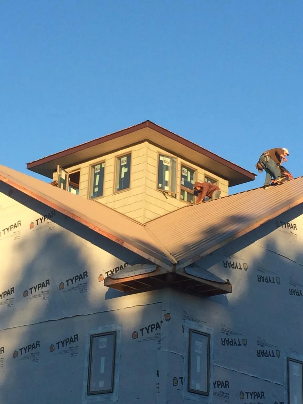 Roofers working around a rooftop cupola on a new metal roof at sunset — Roof Waterproofing in Evanston by Roofing Brothers